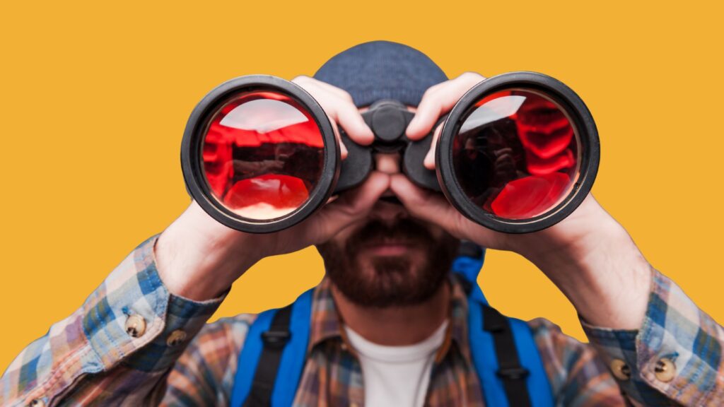 Man looking through binoculars signifying discovery