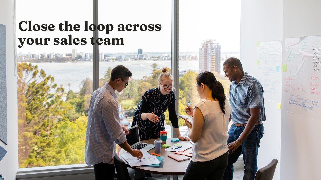 Sales team standing around a table discussing a deal they recently won or lost